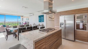 Una cocina moderna con una isla central, electrodomésticos de acero inoxidable y un amplio ventanal con vistas a la ciudad.