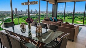 Un comedor moderno con mesa de vidrio, sillas de cuero y vista a la ciudad.