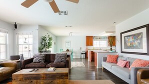 A spacious living room with a wooden coffee table, two sofas, and a dining area in the background.
