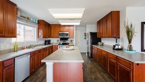 A modern kitchen with wooden cabinets, a central island, a microwave, a refrigerator, and a dishwasher.