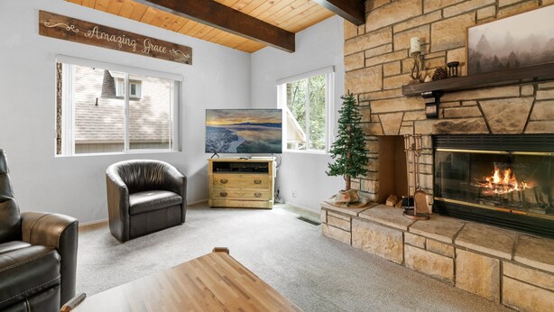 Ein gemütliches Wohnzimmer mit Kamin, Ledersesseln, einem Holztisch und einem Bild an der Wand.
