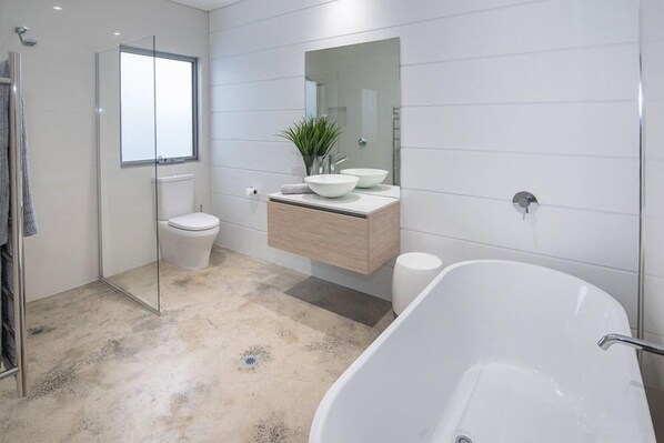 A modern bathroom with a freestanding bathtub, a glass shower enclosure, a toilet, and a vanity with a mirror and plant. - Gracetown, Margaret River - perfect getaway house! (Gracetown)