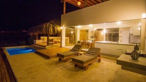 Una villa moderna con piscina, sillas de descanso y zona de comedor.