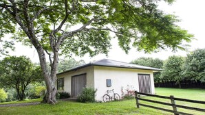 A small, single-story building with a sloped roof, surrounded by lush greenery and trees. - Byron Hinterland Retreat - Honeymoon (Repentance Creek)