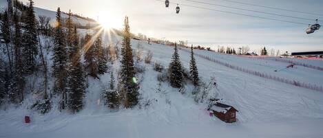 Una pista de esquí nevada con un telesilla y una cabaña pequeña.