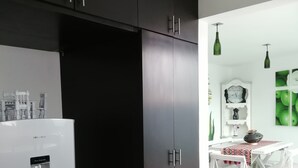 A modern kitchen with dark cabinets, a white refrigerator, and a dining area with a white table and chairs.
