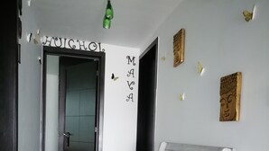 A hallway with a white bench, a green hanging light fixture, and a wall with decorative elements including a Buddha head and butterflies.