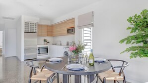 A modern kitchen with white cabinets, a built-in oven, and a microwave.
