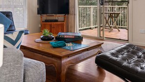 A living room with a wooden coffee table, a television, and a Scrabble game set.