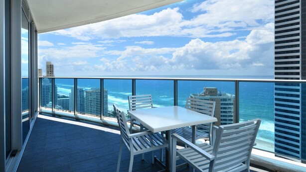 A balcony with a white table and chairs, overlooking a cityscape and the ocean. - Wake Up In Paradise, Luxury Surfers Paradise Apt (Surfers Paradise)