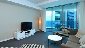 A modern hotel room with a large balcony, a flat-screen TV, a sofa, a coffee table, and a white entertainment unit. - Wake Up In Paradise, Luxury Surfers Paradise Apt (Surfers Paradise)