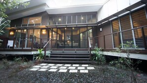 Un edificio moderno con vestíbulo cubierto, amplias ventanas y una escalera que conduce a la entrada principal.