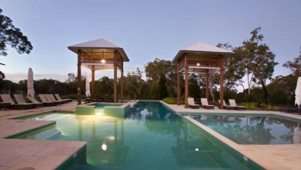 Un área de piscina con dos gazebos y sillones de descanso.
