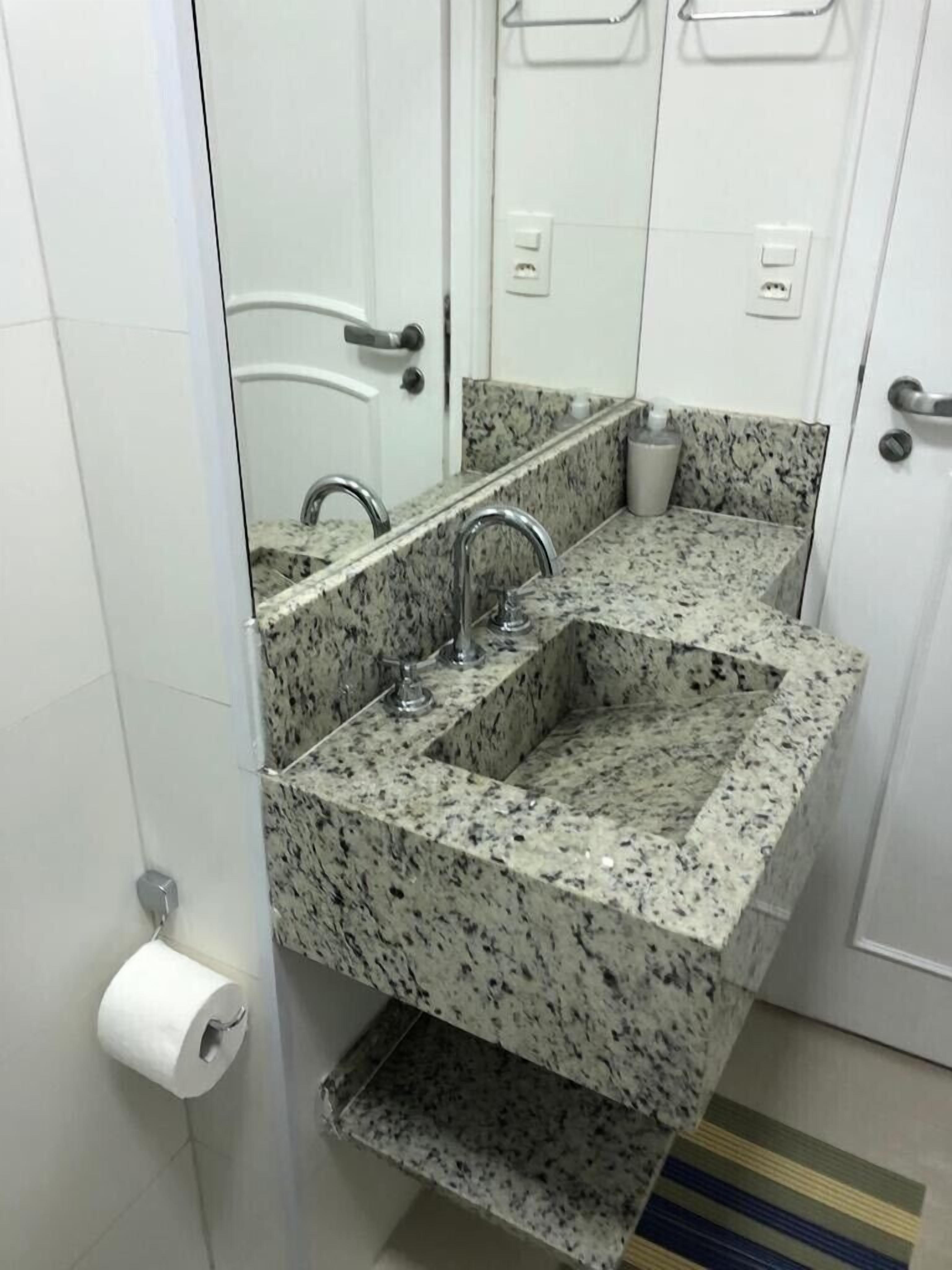 Un bagno con lavandino in granito, uno specchio e un portasciugamani.