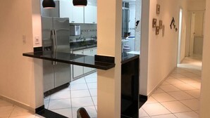 Een moderne keuken met een glazen wand, roestvrijstalen apparatuur en hanglampen.
