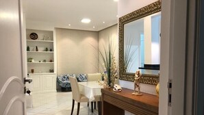 Een eethoek met een witte tafel, stoelen en een decoratieve spiegel boven de bar.
