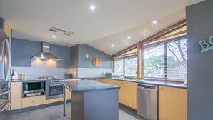 A modern kitchen with a central island, built-in oven, microwave, and dishwasher.
