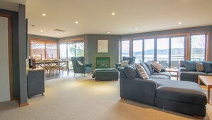 A spacious living room with a fireplace, comfortable seating, and large windows offering a view.