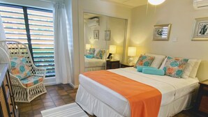 Un dormitorio con cama, una silla, un espejo y una ventana con persianas.