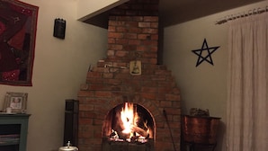 Een gezellige kamer met een metselwerk open haard, een ster decoratie aan de muur en een boekenkast met boeken en een fotolijst.