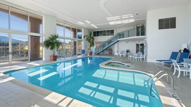 Una piscina interior de diseño curvo, rodeada de sillones de descanso y plantas en macetas.