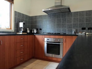 Enjoy cooking in this well-equipped kitchen with a stainless steel oven, gas stove, and range hood.