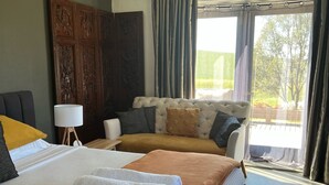 Een hotelkamer met een groot bed, een bank, een wand van hout en uitzicht op de omgeving.