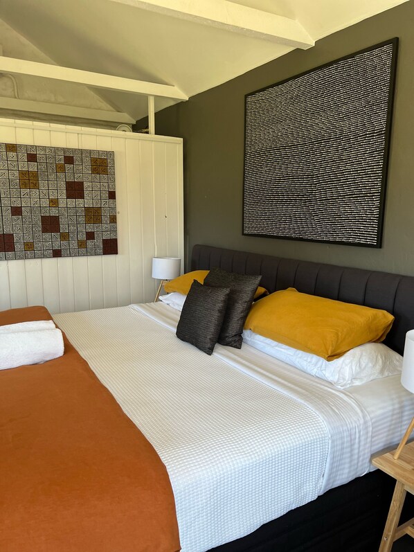 A neatly made bed with a white and brown bedspread, two pillows, and a brown throw blanket.