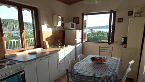 Una cucina con vista sul mare, un tavolo da pranzo con sedie e un frigorifero.