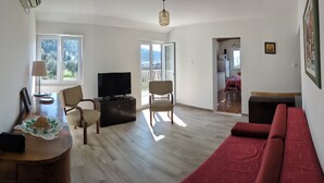 Un'ampia zona giorno con un divano rosso, mobili in legno, una televisione a schermo piatto e un'area pranzo con tavolo e sedie.