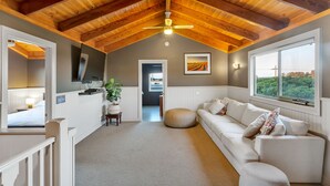 A spacious room with a high ceiling, a white sofa, a dining table, and a large window.