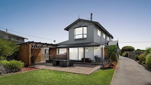 A modern two-story house with a patio, a covered outdoor seating area, and a well-maintained lawn. - Heated Indoor pool & outdoor spa, next to beach!  Welcome your holiday paradise! (Surf Beach)
