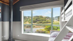 A bedroom with a large window, a bunk bed, and a radiator.