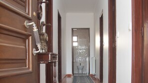 Ein Flur mit Holztüren, einem gemusterten Teppich und Blick in einen Raum mit Toilette und Heizkörper.