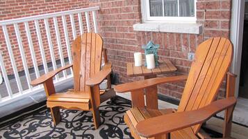 A wooden chair and table set against a brick wall with a window above.