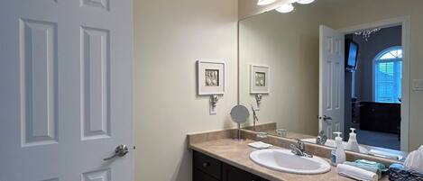 A bathroom with a double sink, dark cabinets, a large mirror, and a light fixture above the mirror.