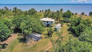 Una propiedad costera con una casa, palmeras y vista al océano.