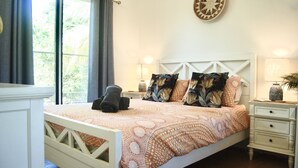 Un dormitorio con una cama, dos mesitas de noche, un reloj de pared y una ventana con cortinas.