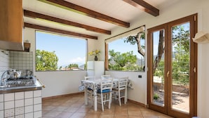A kitchen with a tiled backsplash, a dining area with a table and chairs, and a sliding glass door leading to an outdoor patio. - - VILLA FLAVIA apartment (Sant'Agnello)