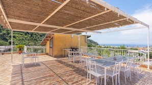 An outdoor patio with white metal tables and chairs, a pergola overhead, and a view of the sea and hills in the background. - - VILLA FLAVIA apartment (Sant'Agnello)