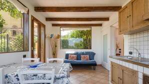 A cozy kitchen with wooden cabinets, a dining area with a table and chairs, and a large window offering a view of greenery. - - VILLA FLAVIA apartment (Sant'Agnello)