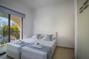 Une chambre avec deux lits, un balcon et une vue sur la verdure.