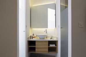 A modern bathroom with a white sink, a mirror, and a wooden vanity.