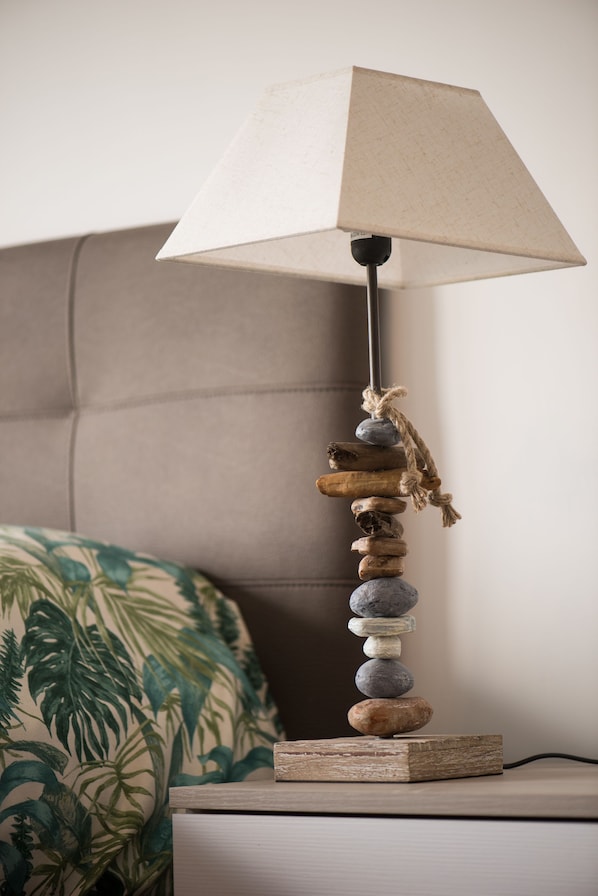A lamp with a textured lampshade, a wooden base, and a rope tied around it, placed on a bedside table next to a bed with a floral-patterned pillow. - Panorama Vesuvius 1 (central) private room in apartment (Napoli)