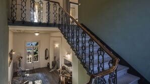 A grand staircase with ornate black railings and a chandelier. - Villa Belvedere in the heart of Chianti (loro ciuffenna)