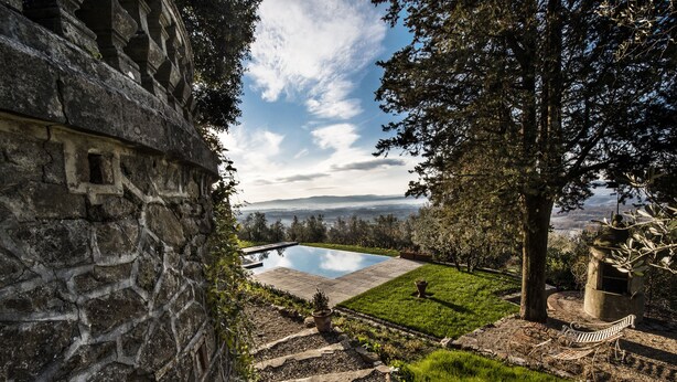 A stone wall, a pool, and a grassy area with a bench. - Villa Belvedere in the heart of Chianti (loro ciuffenna)