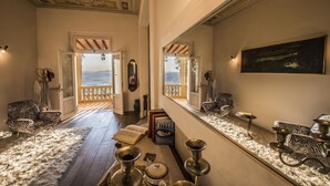 A spacious hallway with a view of the sea, a zebra-patterned chair, a bookshelf, and a decorative mirror. - Villa Belvedere in the heart of Chianti (loro ciuffenna)