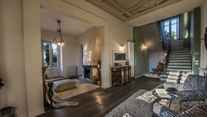 A spacious living room with a fireplace, a staircase, and a view of the outdoors. - Villa Belvedere in the heart of Chianti (loro ciuffenna)