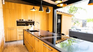 A modern kitchen with wooden cabinets, a black countertop, and a built-in stove. - HOUSE IN THE EBRO DELTA, WITH WIFI, HEATED POOL, PARKING AND BARBECUE. (Deltebre)