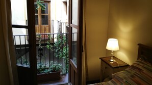 Une chambre d’hôtel avec un balcon, une table de chevet avec une lampe et un lit recouvert d’une courtepointe à rayures.